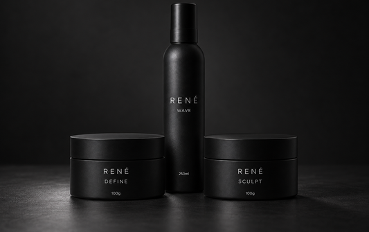 Three black RENÉ haircare containers on a dark surface against a black background: a tall bottle labeled RENÉ WAVE in the center, flanked by two shorter jars labeled RENÉ DEFINE and RENÉ SCULPT.
